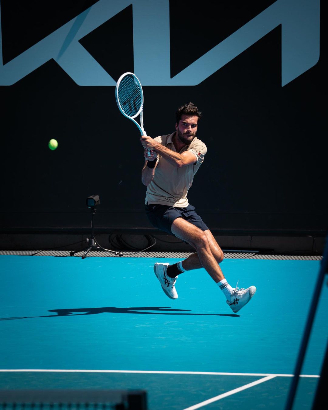 Jules Marie en pleine frappe sur un court de tennis en dur bleu